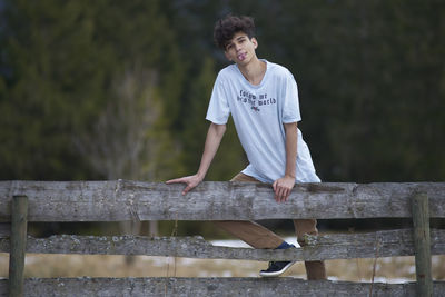 Portrait of man standing by wooden railing