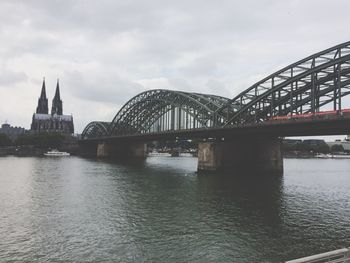 Arch bridge over river against cloudy sky