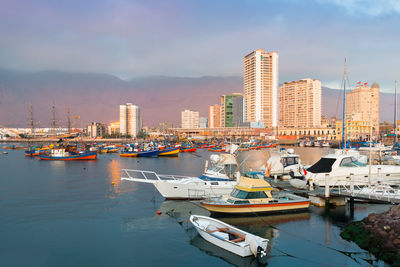 Boats moored in sea against buildings in city