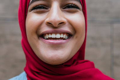 Crop optimistic arab female wearing headscarf standing on street and laughing happily while looking forward