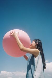 Low angle view of woman standing against clear blue sky