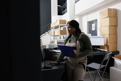 Side view of young woman using mobile phone in office