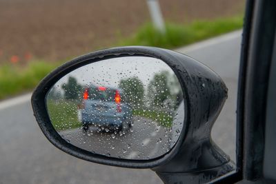 Close-up of raindrops on side-view mirror