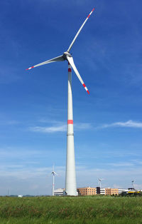 Low angle view of windmill on field against sky