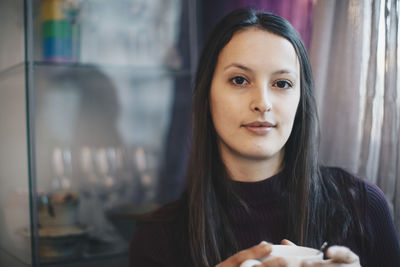 Portrait of young woman holding coffee cup in college dorm room