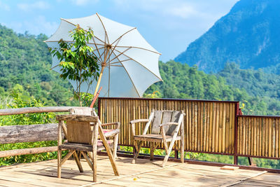 Chairs and table against trees and mountains against sky