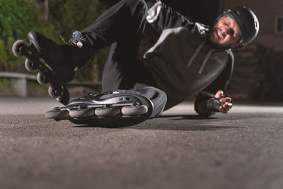 Full length of man fallen while practicing roller skating on road