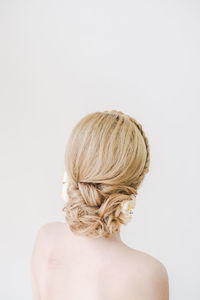 Rear view of shirtless woman with hairstyle against white background