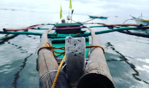 Close-up of boat moored at harbor against sky