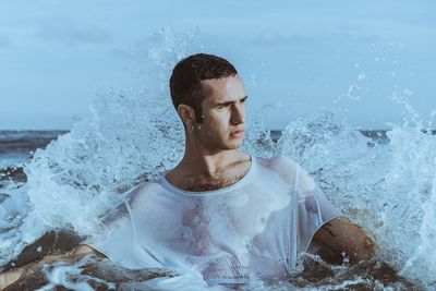 Young man splashing water in sea