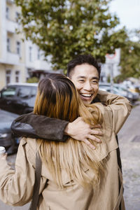 Happy male friend embracing female friend with highlighted hair