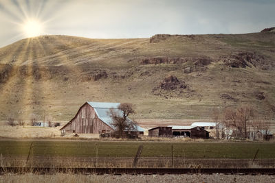 Scenic view of field by houses against sky