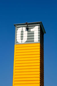 Low angle view of yellow flag against blue sky