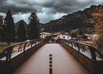 Walkway amidst houses and buildings against sky