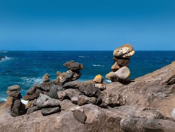 Rocks on beach against clear blue sky