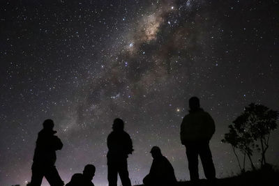 Low angle view silhouette of people standing against sky at night