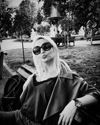 Portrait of young woman wearing sunglasses sitting outdoors