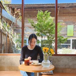 Portrait of young woman using mobile phone while sitting on table