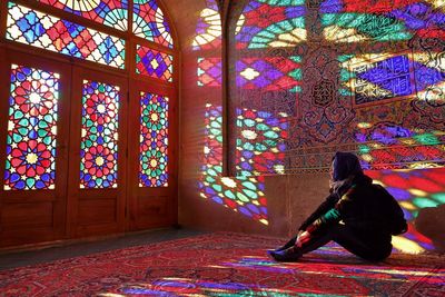 Woman sitting on carpet against stained glass