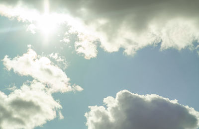 Low angle view of sunlight streaming through clouds