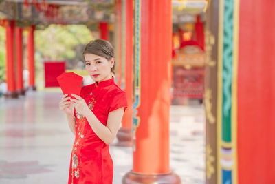 Young woman holding red while standing outdoors