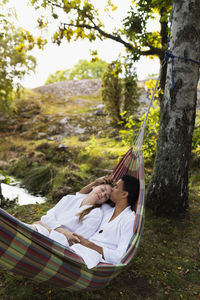 Young couple in bathrobes relaxing in hammock