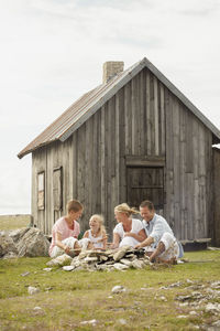 Family sitting near wooden house