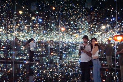 Friends standing on illuminated cityscape at night