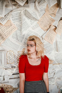 High angel view of young woman standing against papers on wall