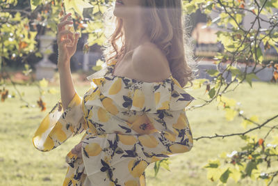 Midsection of woman standing by flowering tree