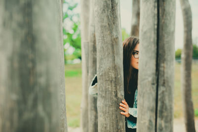 Portrait of woman standing by tree trunk