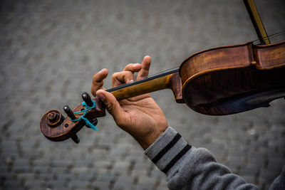 Cropped hand playing violin on footpath