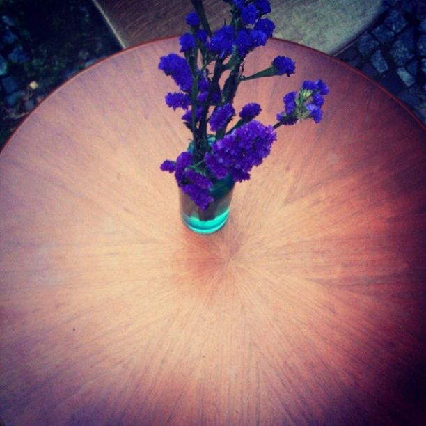 flower, indoors, high angle view, table, freshness, purple, close-up, still life, wood - material, directly above, fragility, art and craft, decoration, petal, no people, creativity, art, multi colored, wooden, blue