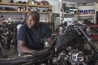 A young man fixing a motorcycle.