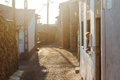 Rear view of woman in alley amidst buildings