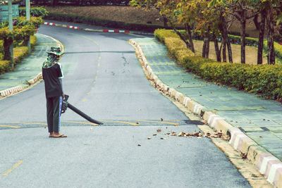 Man walking on footpath by road