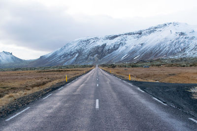 Road leading towards snowcapped mountains against sky