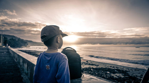 Man looking at sea against sky during sunset