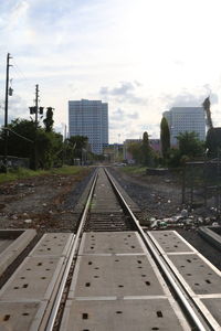 Railroad tracks in city against sky