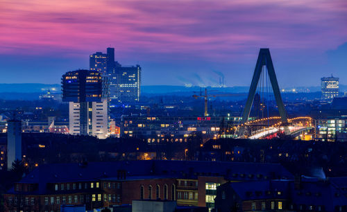 Illuminated buildings in city against sky at sunset