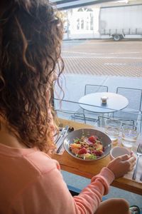 Close-up of woman eating breakfast while sitting at table in restaurant