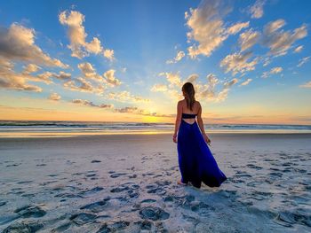 Woman on beach against sky during sunset