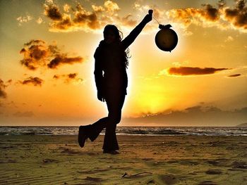 Silhouette man standing on beach against sky during sunset