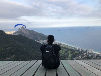 Rear view of man looking at sea against sky