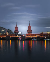 Illuminated bridge over river against sky in city