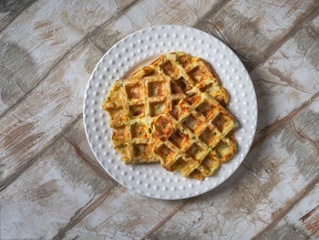 Zucchini waffles on a white plate on a wooden decorative table top view