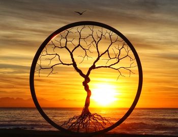 Silhouette tree against sea during sunset
