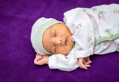 Newborn baby isolated sleeping in white cloth with purple background from different angle