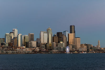 Sea by modern buildings against clear sky