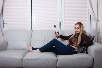 Full length of young woman sitting on sofa